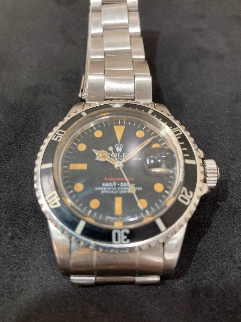 Vintage Rolex Red Submariner 1680 front view — patinated black dial with red SUBMARINER text, black aluminum bezel insert and stainless steel Oyster bracelet
